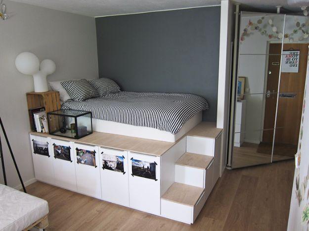 Photograph of a raised platform bed built on white kitchen cabinets with a wooden top and a built in staircase of three steps