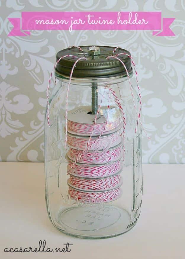Quart mason jar with a daisy cut lid holding six spools of pink and white bakers twine stacked on a bolt, ends threaded out