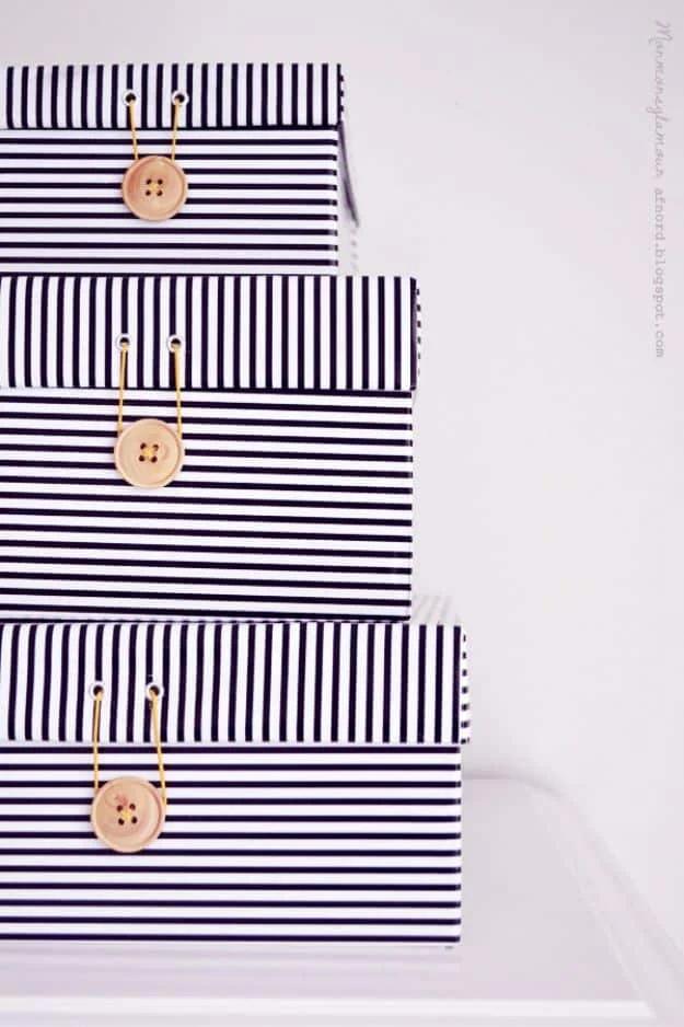 Three stacked shoe boxes covered in black and white striped paper, each lid closed with a wooden button and cord