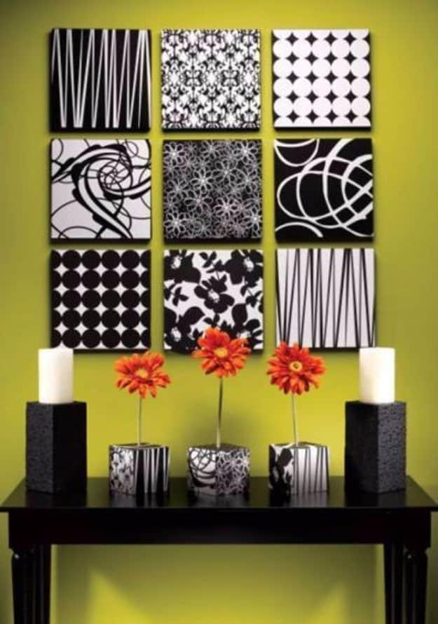 Nine black and white patterned square panels in a grid on a lime green wall above a console with orange flowers