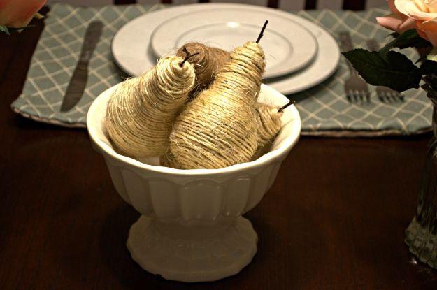 DIY twine pears, three pear shapes wrapped tightly in natural twine, piled in a white footed compote on wood
