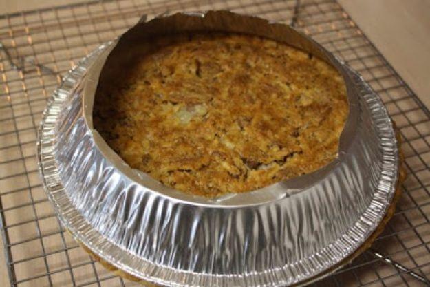 Foil ring made from a cut out pie pan sitting over a baking pie on a cooling rack to shield the crust edge