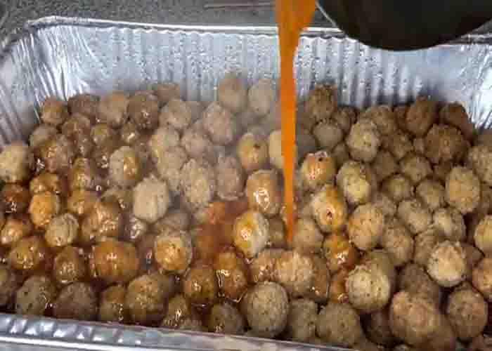 Pouring the sweet chili sauce over the meatballs