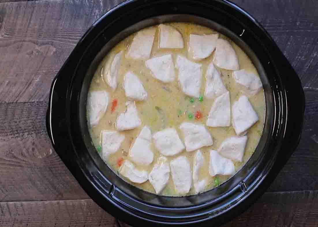 Adding the quartered canned biscuits over the top