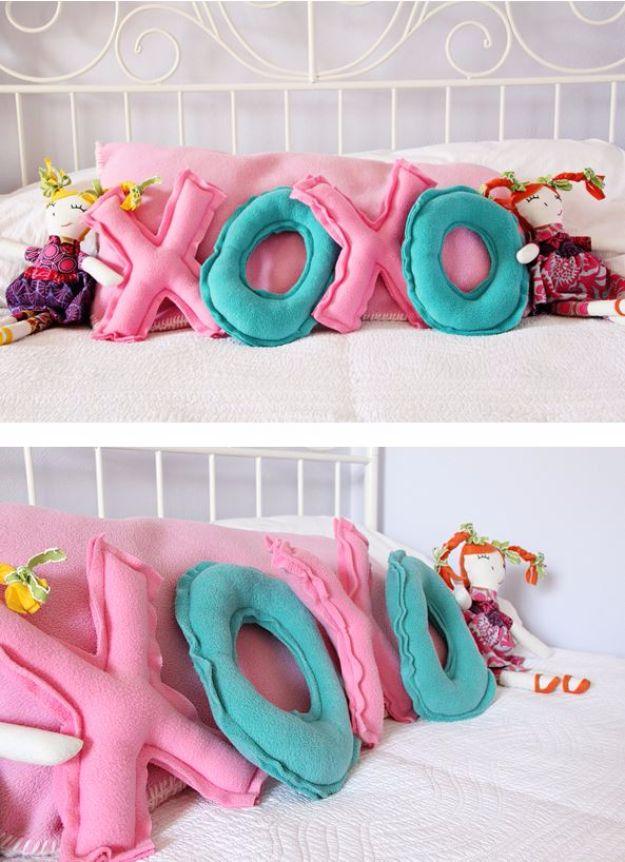 Fabric XOXO letter pillows in pink and red arranged on a sofa for Valentine's Day decor and for gifting