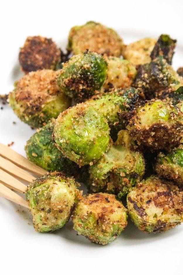 Skillet browned brussels sprouts coated in seasoned bread crumbs, piled on a white plate with a fork