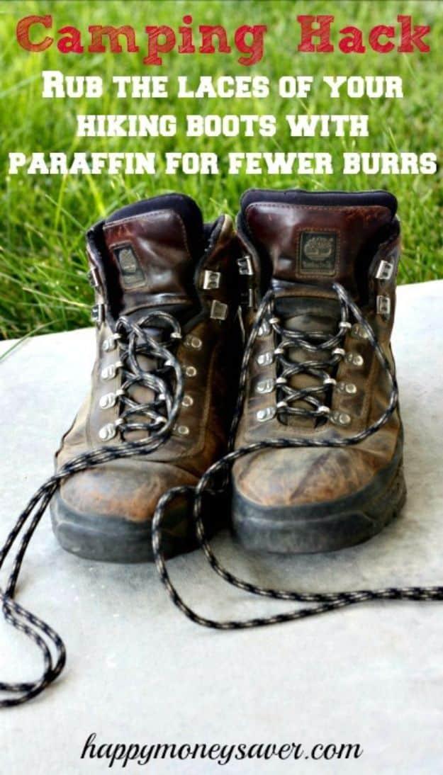 Pair of worn brown leather hiking boots on a table with unlaced cords, under a red typeset Camping Hack banner