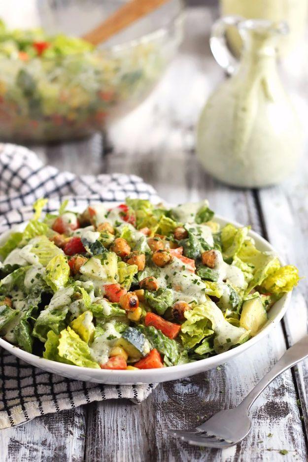 Roasted chickpea salad with chopped romaine and vegetables in a white bowl beside a pitcher of pale ranch dressing