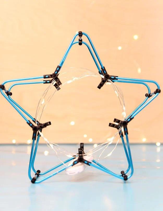 Star shaped night light built from blue aluminum rods and connectors, wrapped in a lit fairy light string