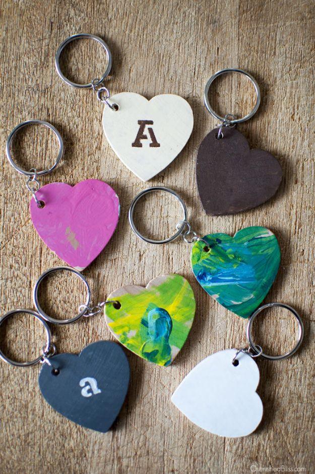 Six painted wooden heart keychains in marbled green, pink, blue and white, some stenciled with a letter, on key rings