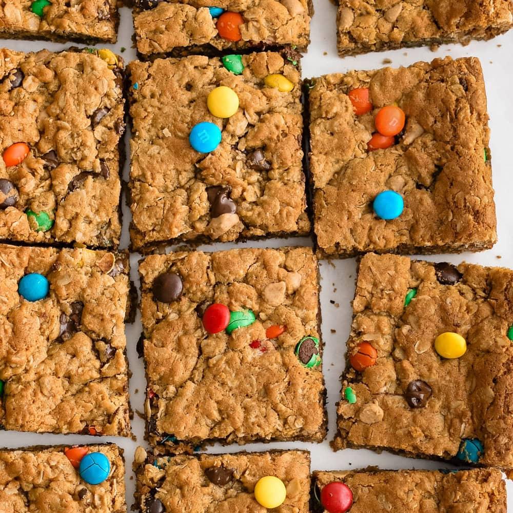 Thick peanut butter oat monster cookie bars cut into squares with candy pieces and chocolate chips for Halloween