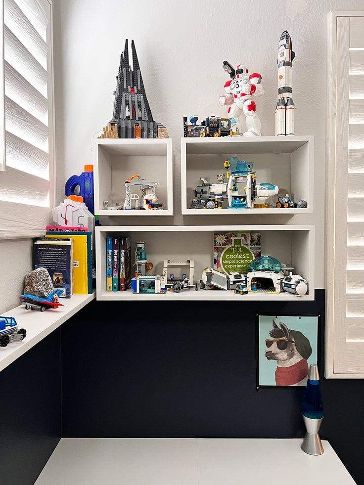 Shadow box wall shelves, three staggered white open boxes mounted on a wall, filled with built models and books