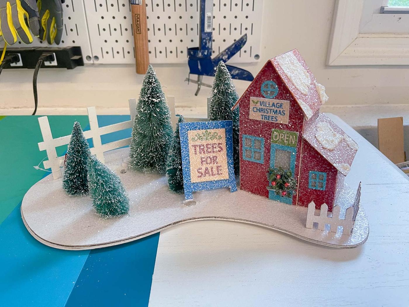 Large glass bowl snow globe on a painted wooden base holding a small winter scene with fake snow inside