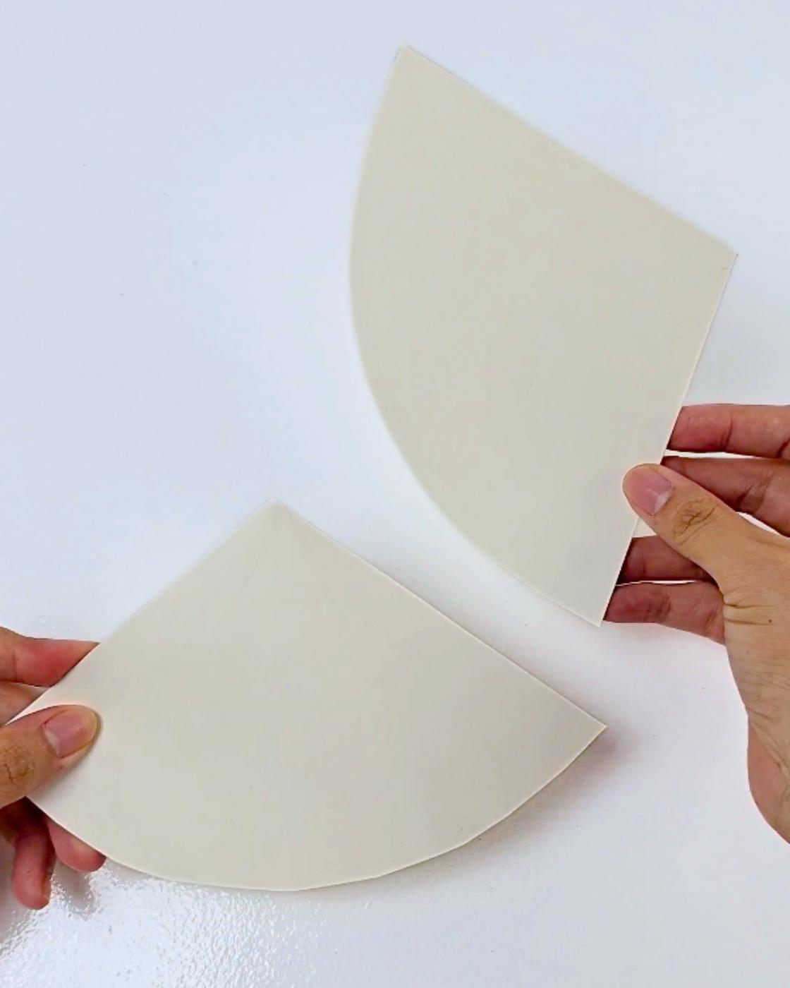 Cardboard Crafts - two hands holding cardboard triangles, the flat shapes that become the headdress cones