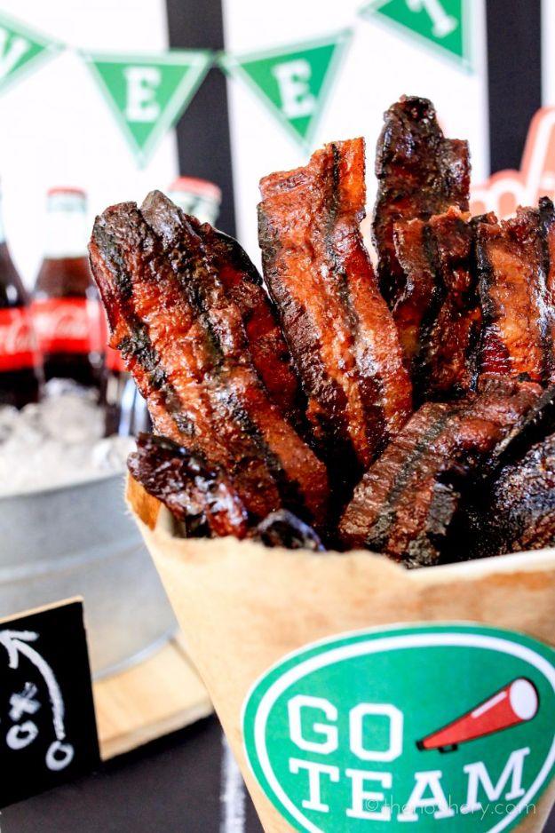 Coca Cola bacon candy, dark glazed bacon strips standing upright in a paper cone beside a Go Team chalkboard sign