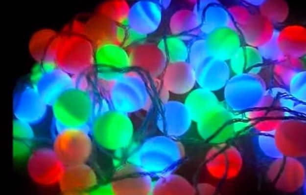 Tangle of glowing ping pong ball string lights in red, blue, green and pink, lit against a dark background