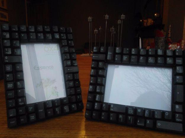 Two black photo frames with borders made entirely of black computer keyboard keys, standing on a dark surface