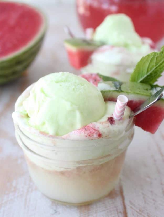 Green lime sherbet float in a mason jar with pink watermelon soda and mint, sliced watermelon behind