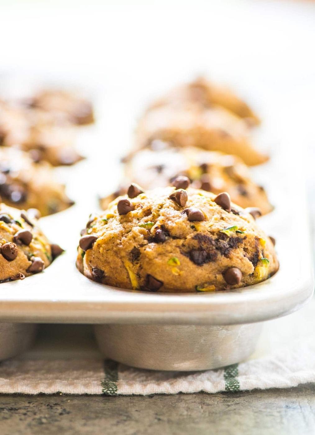 Healthy zucchini muffins with chocolate chips and flecks of green zucchini still in a metal muffin tin