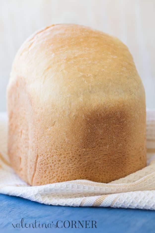 Bread machine white bread loaf turned out of the pan with a tall domed golden crust, cooling on a rack