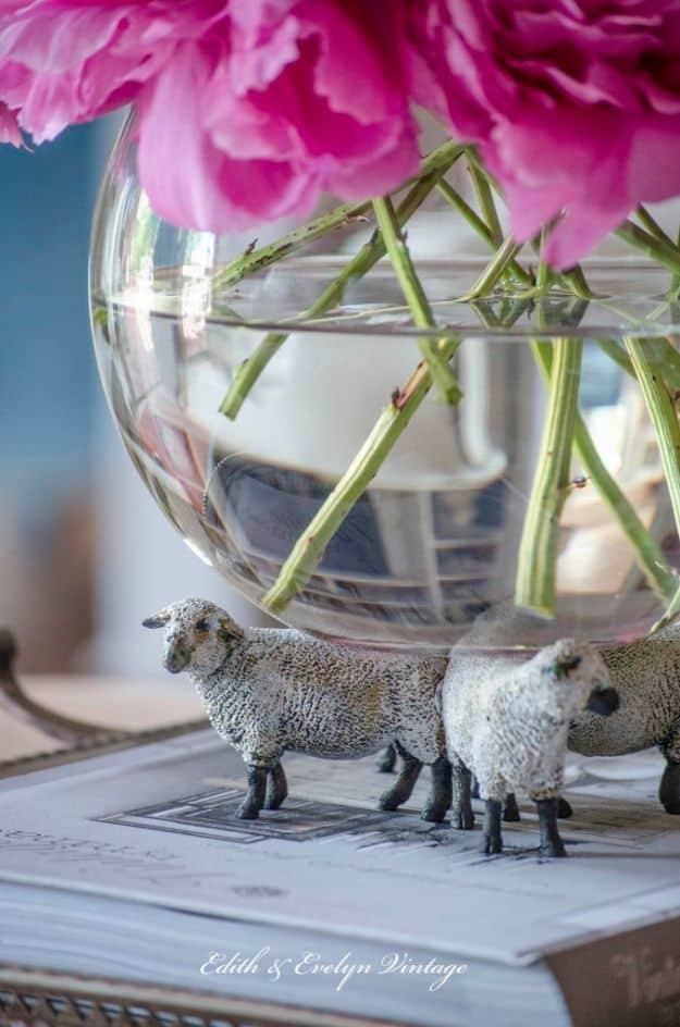 A small white painted sheep figure on a stained wood base sits on a shelf like a piece of farmhouse sculpture