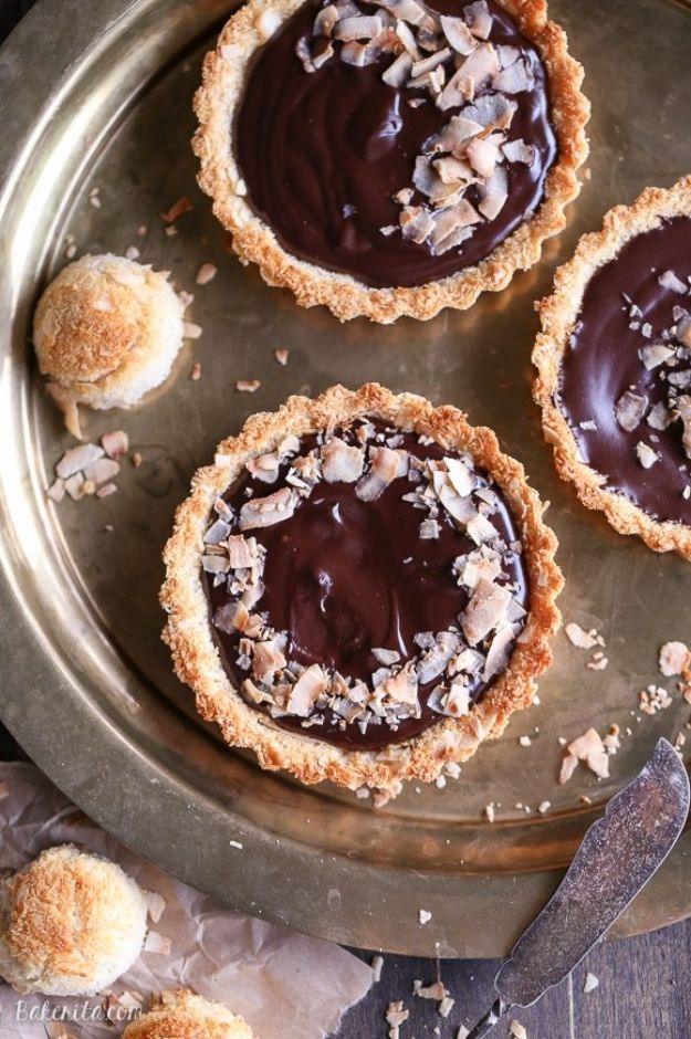 Chocolate ganache tarts in coconut macaroon crusts scattered with toasted coconut on an antique metal tray