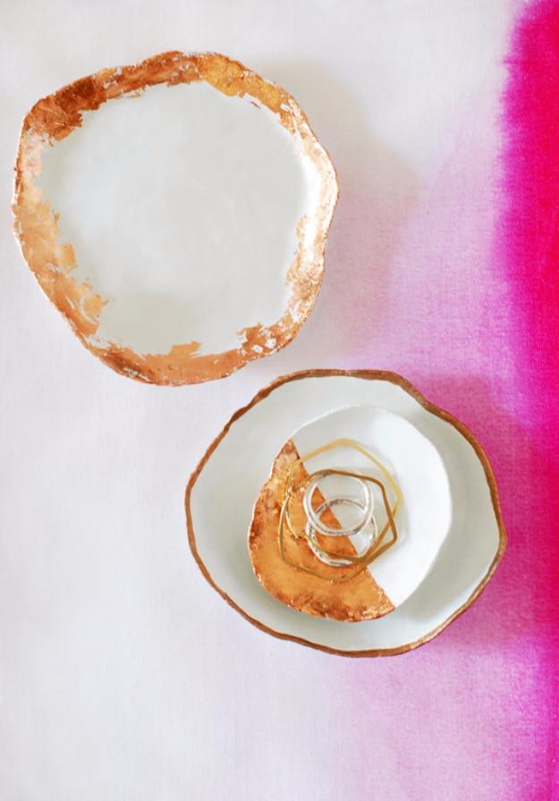 Handmade jewelry dishes with copper touches, two white air dry clay dishes with uneven copper leaf rims holding gold rings