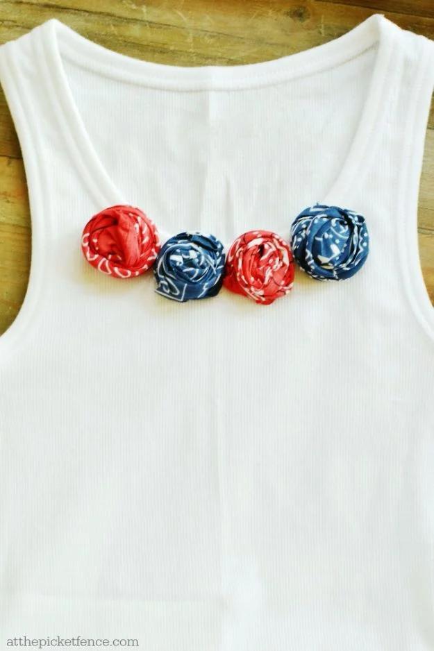 White tank top with four red and navy rolled bandana rosettes pinned in a row across the chest of the shirt