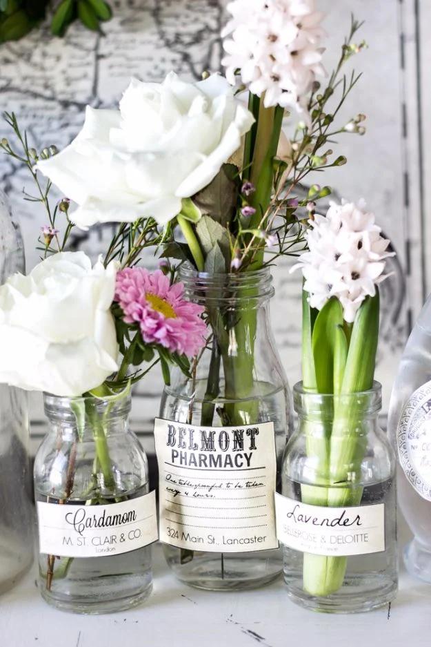 Spring apothecary jar labels printable on three glass bottles holding white roses and pink hyacinths against a map
