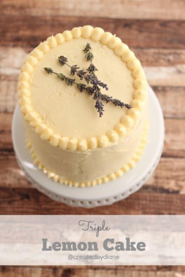 Pale yellow triple lemon cake with a beaded piped border and sprigs of lavender on top, on rustic wood