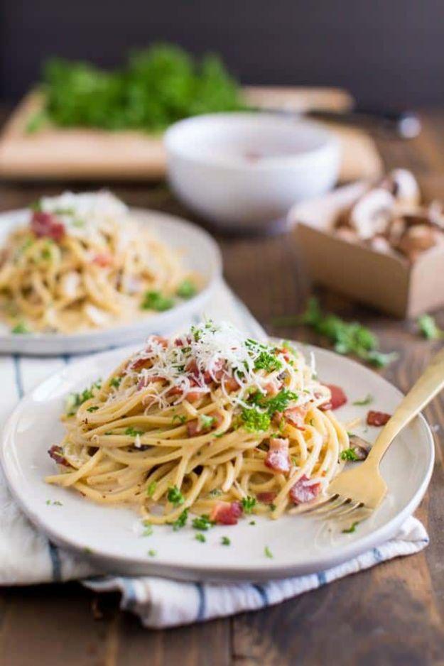 Creamy bacon spaghetti carbonara on a white plate, pasta in cream sauce with bacon pieces and chopped parsley