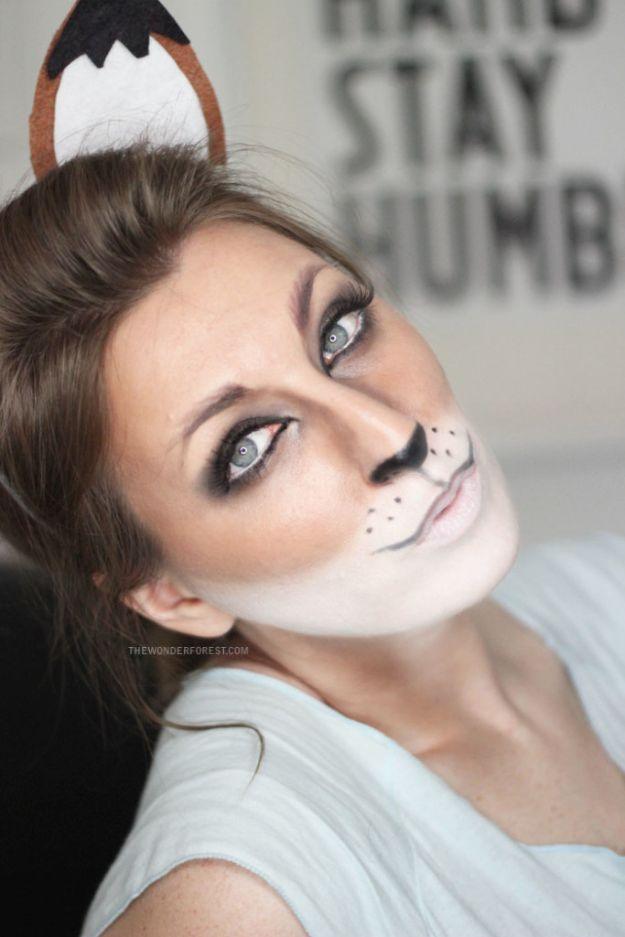 Cute fox Halloween makeup with white muzzle paint, a black nose, drawn whiskers and brown ears on a headband