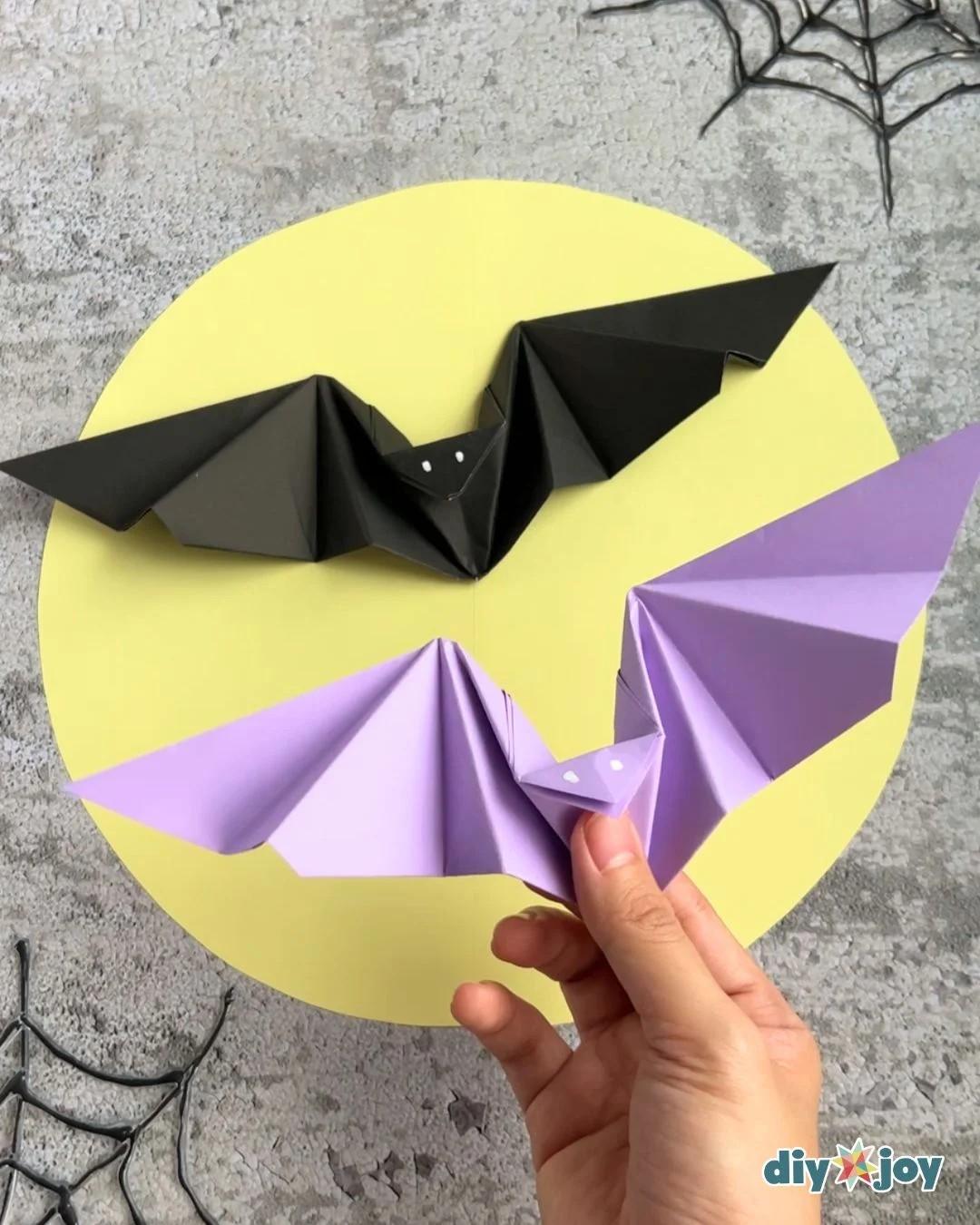 Paper bat origami finished and standing upright, folded from a single sheet of paper with wings that flap.