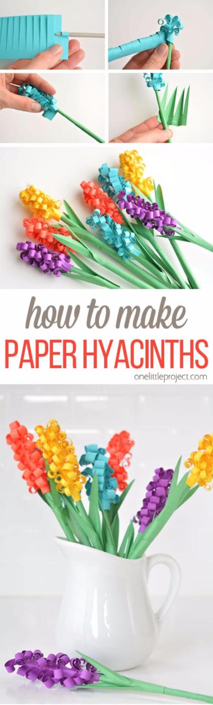 Paper hyacinth flowers, rainbow fringed paper hyacinths on green stems standing in a white pitcher on a white surface