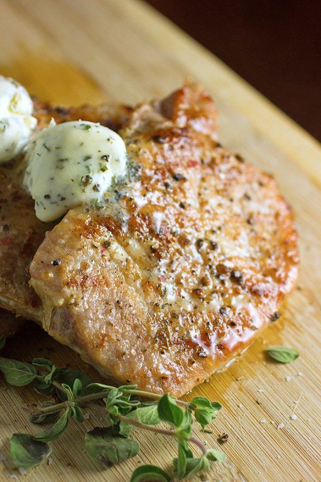 Easy grilled pork chop topped with a swirl of herb butter melting over the top on a wooden board with oregano