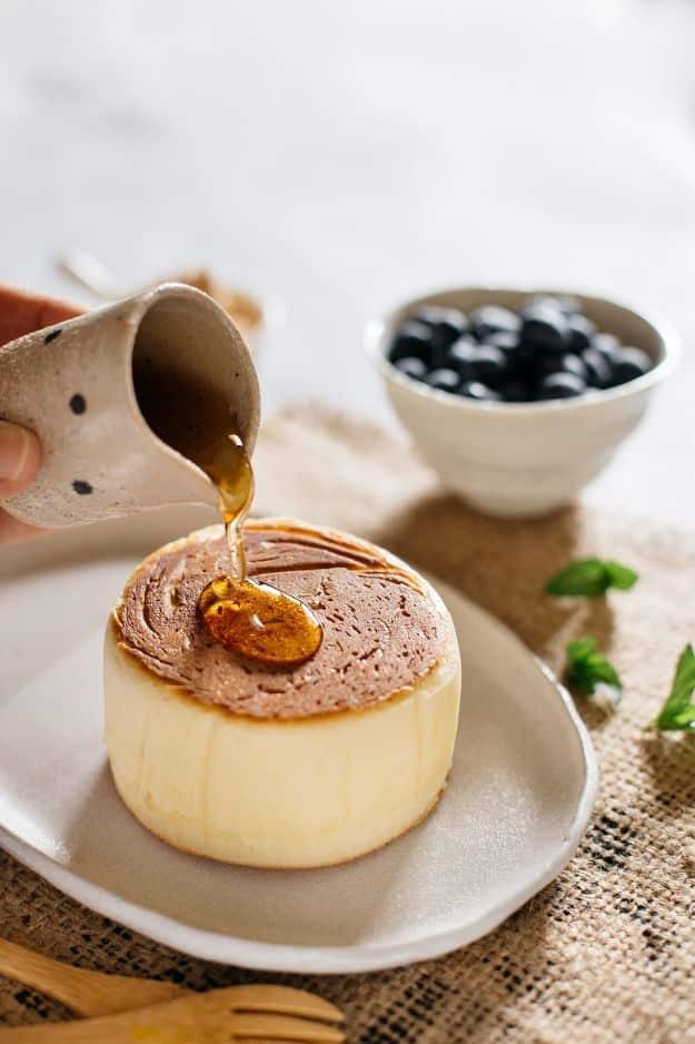Extra thick and fluffy Japanese pancake on a plate with syrup being poured over from a small ceramic jug