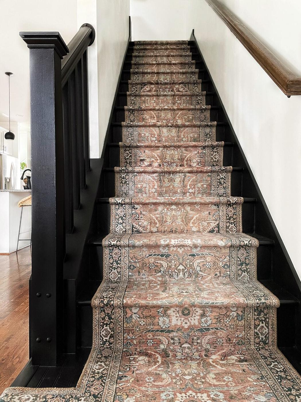 Staircase with a patterned Persian style runner up the middle and dark painted risers, stringer and newel post