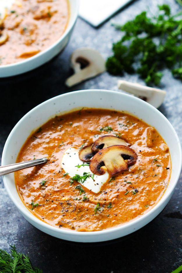 Hungarian mushroom soup in a white bowl with a swirl of sour cream, two browned mushroom slices and fresh dill