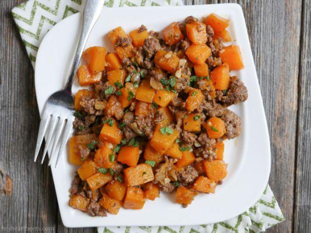 Spicy ground beef and butternut squash served on a white plate with cubed squash, beef and fresh herbs
