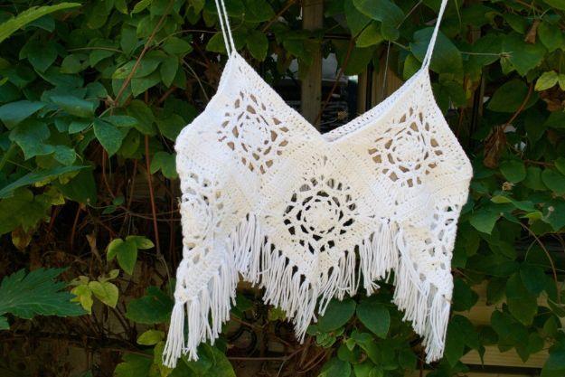 Cream crochet granny square crop top with a long fringe hem, hanging on straps against green ivy leaves