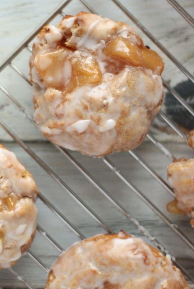 Baked gluten free apple fritters on a sheet pan, glazed and studded with chunks of chopped fresh apple