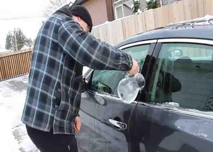 Pouring lukewarm water to the car door to defrost it