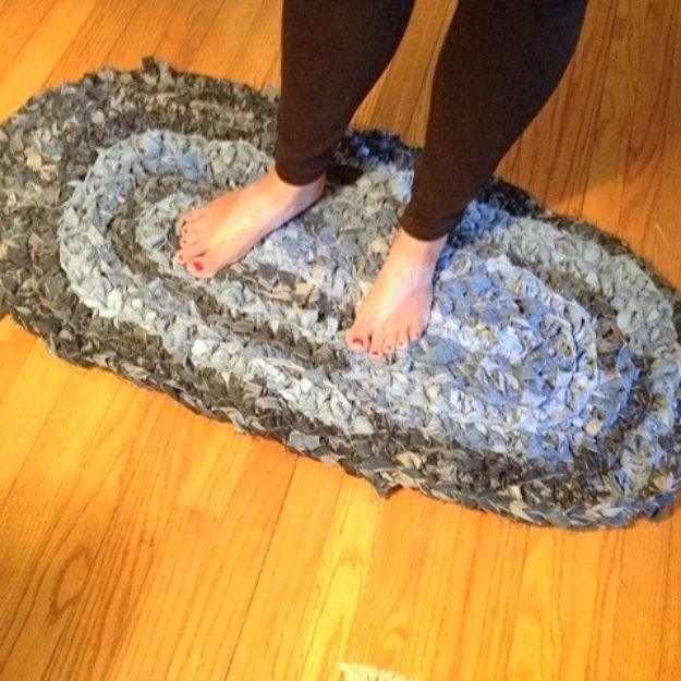 Oval knotted denim rag DIY rug in graded blues from light centre to dark edge, bare feet standing on it