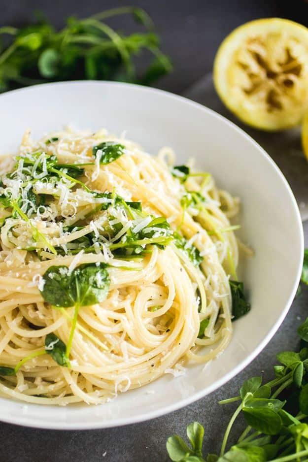 Simple lemon pasta with parmesan and pea shoots, spaghetti in a bowl topped with grated cheese and greens