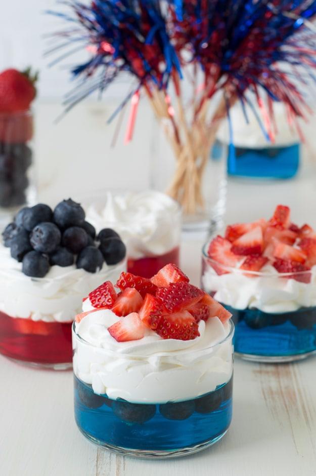 Layered red and blue jello cups topped with fresh berries and whipped cream for a five ingredient dessert