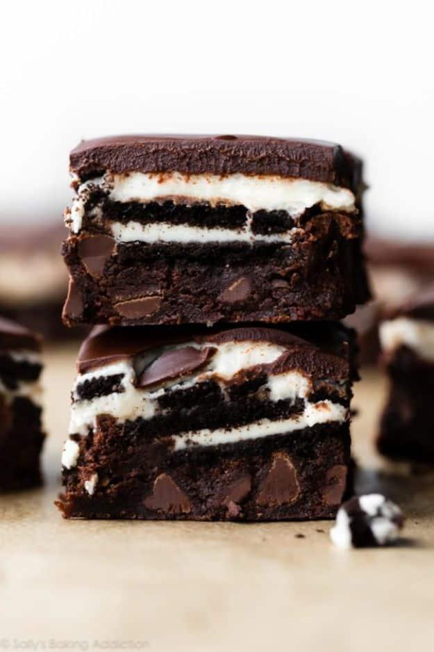 Cookies and cream brownies in a tall stack with whole Oreo layers, buttercream and a poured chocolate top