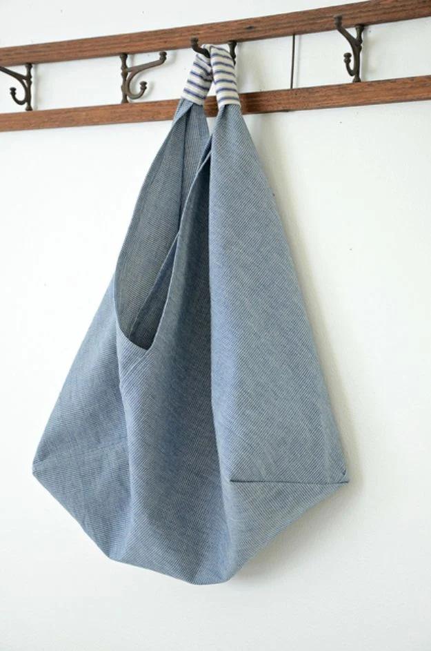 A folded origami market bag in navy canvas with a contrasting handle, standing upright on a wooden floor.