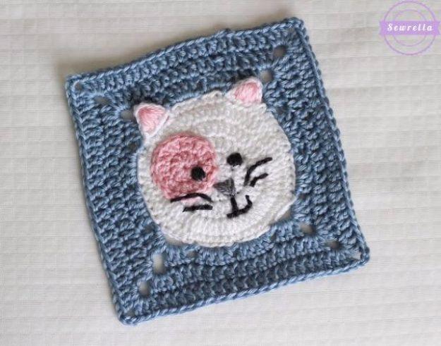 Kitty cat crochet granny square, a white crochet cat face with pink muzzle and ears inside a blue and grey square border