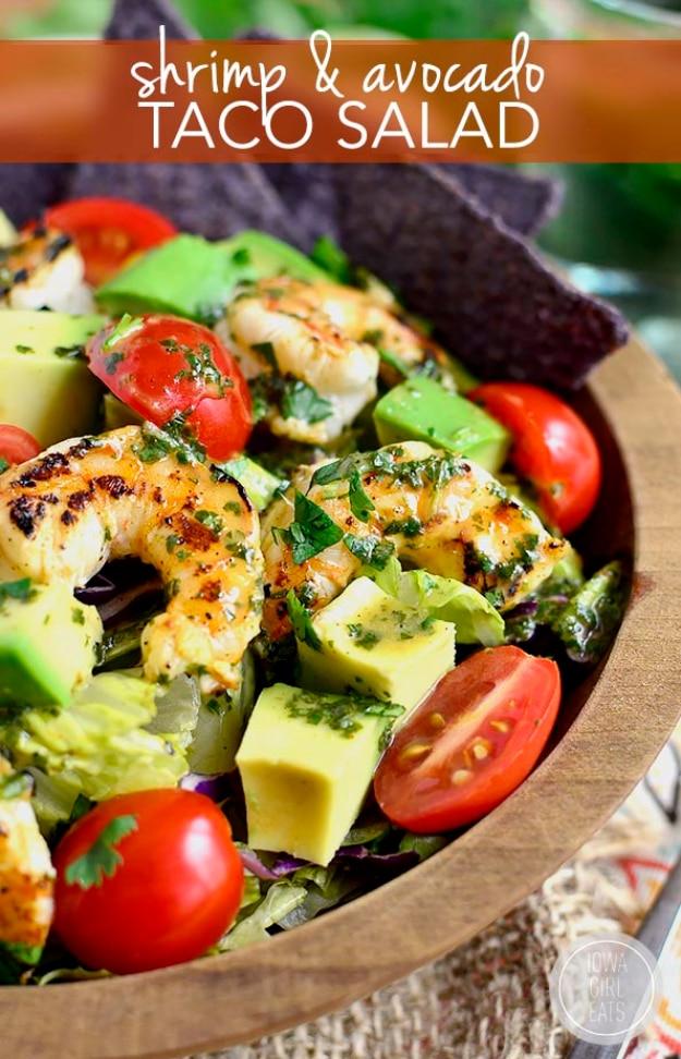 Typeset pin graphic of a wooden bowl of taco salad with grilled shrimp, avocado, tomatoes and blue corn chips
