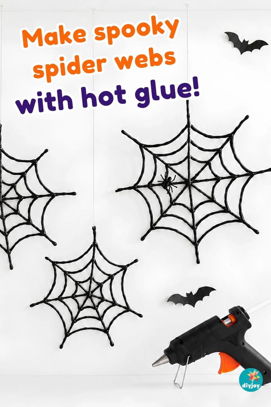 Spider Web Decorations - three black hot glue webs mounted on a wall with paper bats and a plastic spider nearby